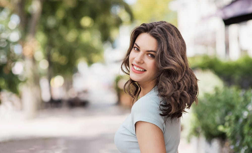 Beautiful happy young woman closeup outdoor portrait - Cosmetic Dentistry in Seattle